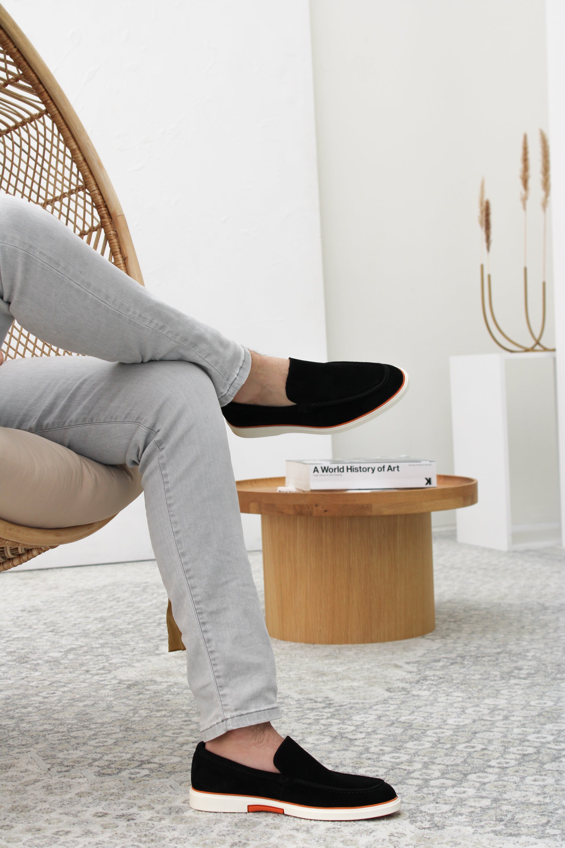 Heritage Suède Loafer Zwart – gecombineerd met een zakelijke outfit op een stenen achtergrond.